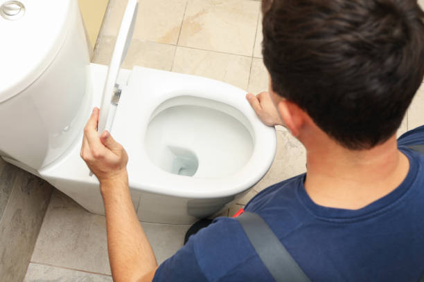 istock The plumber in overalls fixes the toilet 1279274812
