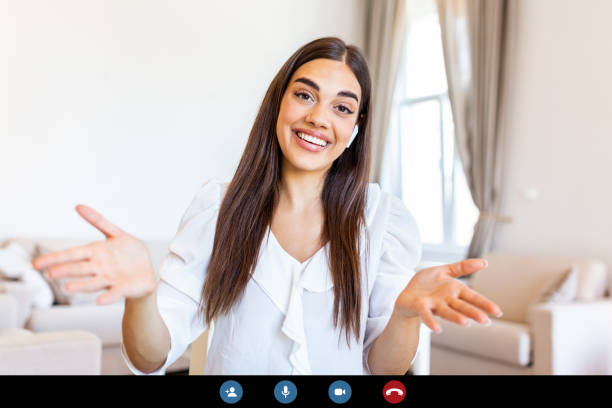 istock Attractive young woman smiling and looking at camera while having video call. Online teaching. Young woman wearing headphone 1279276893