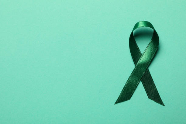 istock Green awareness ribbon on green background, top view 1279276930