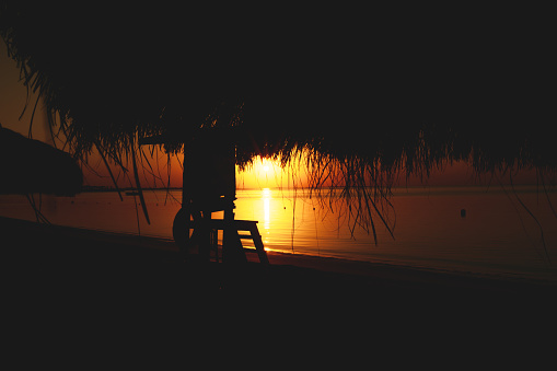 Copyspace of a vibrant sunrise scene in from of empty Egyptian sea. The roof of a parasol area hangs.