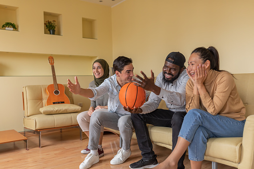 A Large Group of Enthusiastic Young Friends is Spending a Time Together in the Living Room of Their Home and Enjoy a Basketball Game.