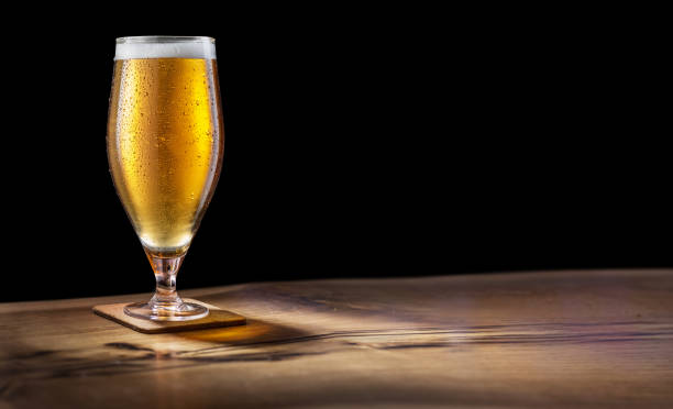黒い背景のバーカウンターに軽いビールのグラス。クリッピングパス。 - beer bar counter bar beer glass ストックフォトと画像