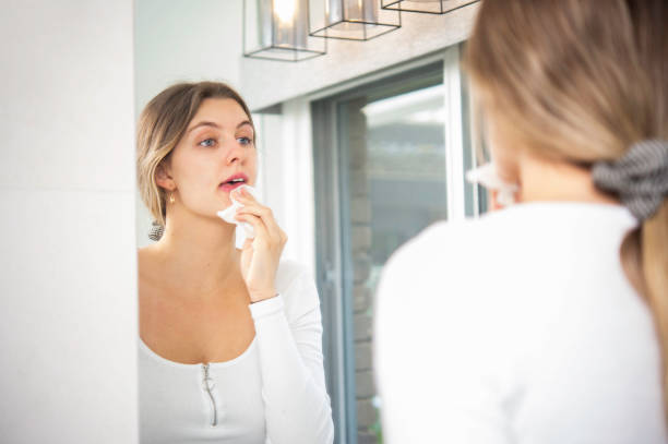 istock Young Woman Wiping Makeup off Face in Bathroom 1279279410