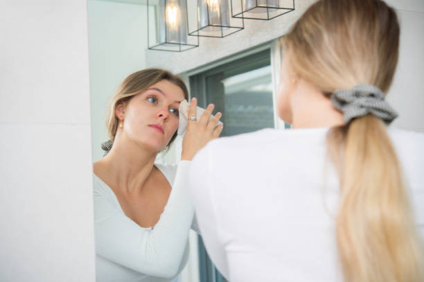 istock Young Woman Wiping Makeup off Face in Bathroom 1279279449