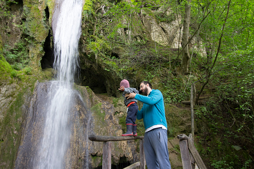 Father with son
enjoying the mountain, standing under the waterfall