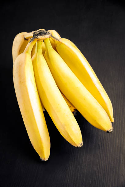istock Bunch of bananas on a black wooden table 1279283116