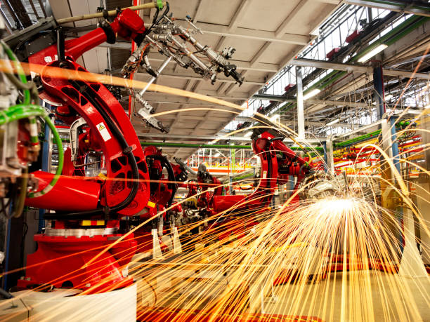 Robotic arms Robotic arms on duty in a car factory. automatic welding torch stock pictures, royalty-free photos & images