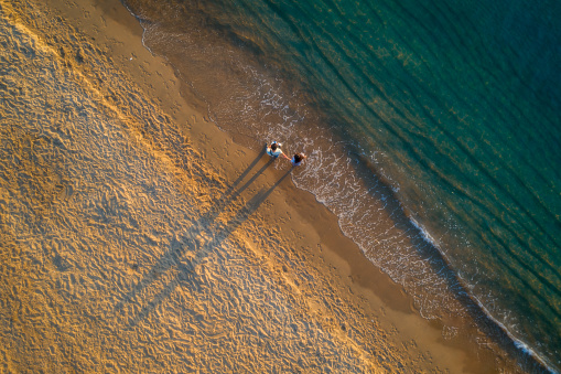 Drone view of Nha Trang beach in early morning with golden sand, golden sunlight and turquoise ocean. Khanh Hoa province, central coastal Vietnam