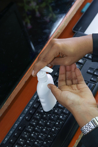 hygiene, health care and safety concept - indian woman using antibacterial hand sanitizer at home office