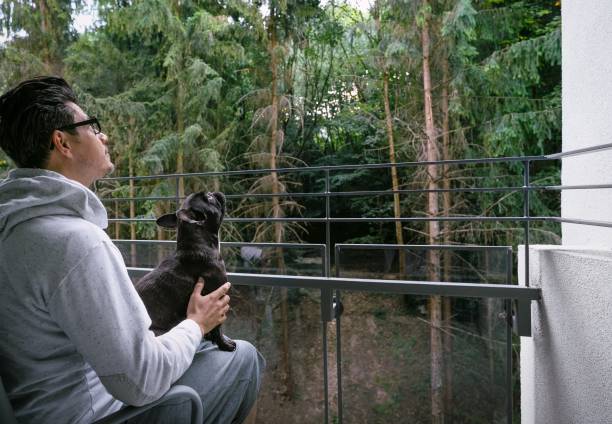 istock Man With Dog Sitting In Balcony Against Trees 1279287412