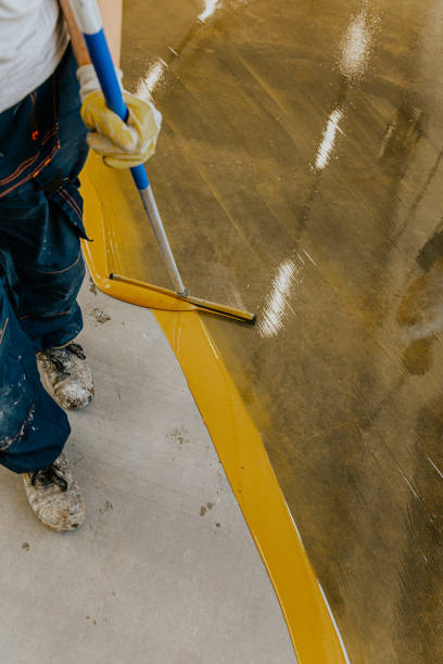istock Worker, coating floor with self-leveling epoxy resin in industrial workshop. 1279290063