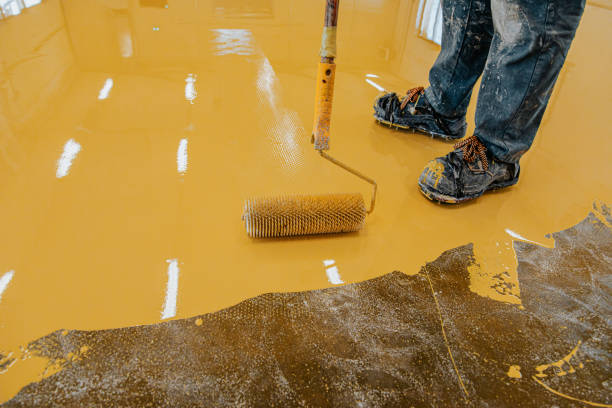 istock Worker, coating floor with self-leveling epoxy resin in industrial workshop. 1279290218