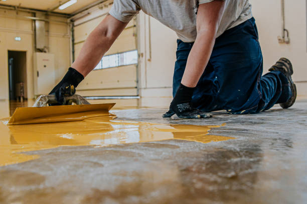 istock Worker, coating floor with self-leveling epoxy resin in industrial workshop. 1279290310