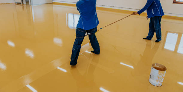 istock Worker, coating floor with self-leveling epoxy resin in industrial workshop. 1279290397