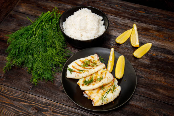 istock Grilled squid with a rice, lemon and greens. Wooden background 1279290618