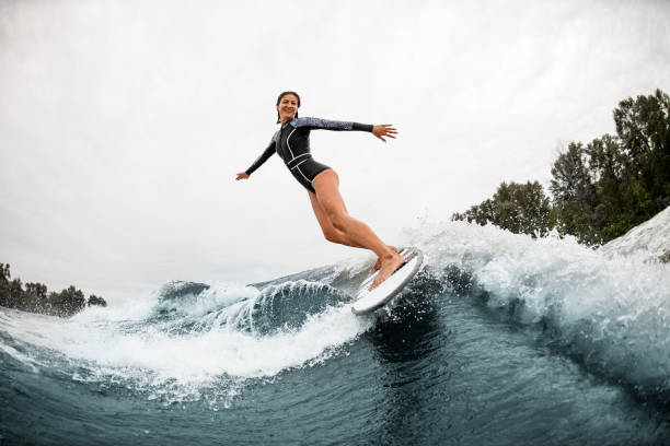 istock beautiful smiling woman elegantly stands on the board and rides down the wave 1279292303