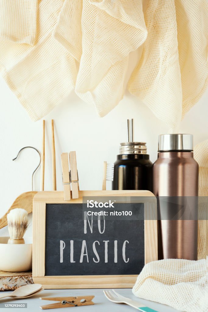 no-plastic sustainable items and text zero waste the text no plastic in a chalkboard and a pile of no-plastic sustainable items, such as metal water bottles, a glass bottle, shopping mesh bags or reusable wooden cutlery and chopsticks Alternative Lifestyle Stock Photo