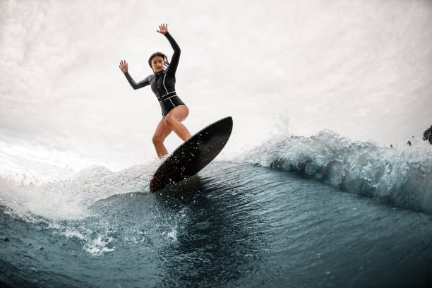 istock young woman stands on a surfboard and actively balances on the wave 1279294083