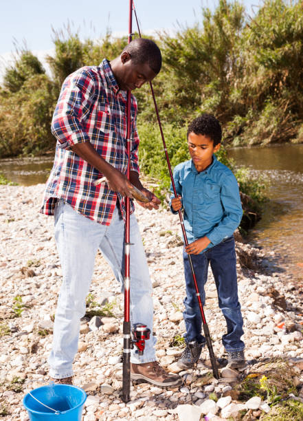 Happy father and his little son fishing together outdoors