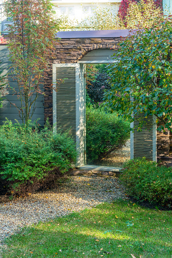 one of the landscape design techniques is the use of a mirror in the garden wall, which is framed like a door, which creates the illusion of a passage to another space