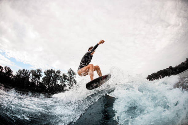 istock Active sportive woman in black wetsuit effectively jumps on surfboard on wave 1279297733