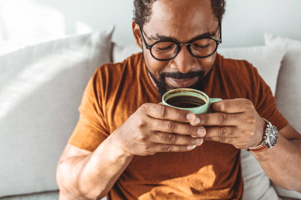 Enjoying the peace of a Saturday morning Cropped shot of a handsome young man relaxing with a cup of coffee drinking stock pictures, royalty-free photos & images