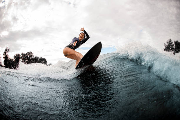 istock cheerful woman in black wetsuit effectively rides on surf board on wave 1279300043