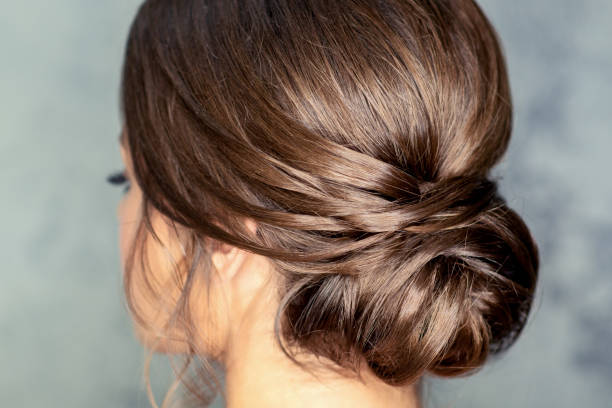 Brunette woman with middle bun hairstyle Rear view of young brunette woman with beautiful middle bun hairstyle on gray background bridal hairstyle stock pictures, royalty-free photos & images