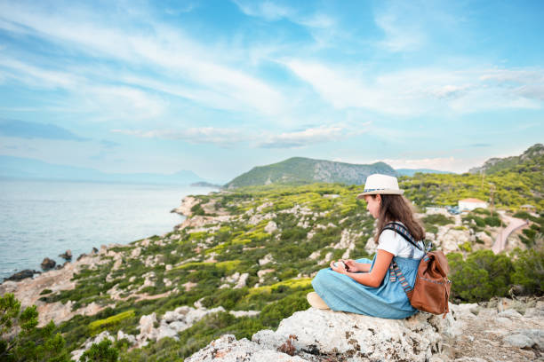 istock Hipster young girl with bright backpack enjoying panoramic mountain sea, using map and looking distance. Tourist traveler on background landscape Barcelona view mockup, sun flare in trip holiday 1279301164