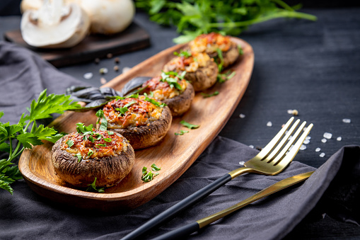 Baked stuffed mushrooms on a wooden plate, soft focus, free space for text. High quality photo