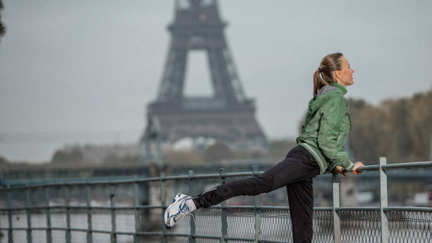 молодая женщина-туристка тренируется возле реки сены с эйфелевой башней на заднем плане - yoga winter urban scene outdoors стоковые фото и изображения