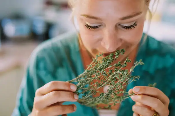 Woman smells fresh herbs, part of a 10 photo series, creative color editing with added grain