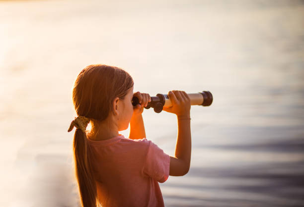 istock Little girl looking through telescope outside 1279306596