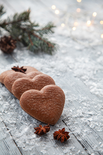 Christmas gingerbread in the form of a heart on a snowy wooden background.Christmas greeting card.