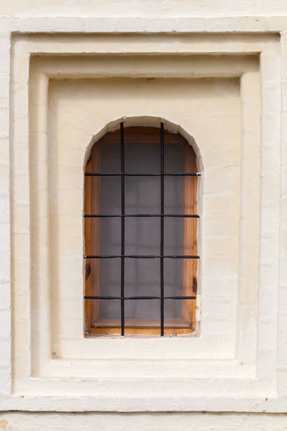 istock Small window with metal grate in an ancient stone wall 1279310036