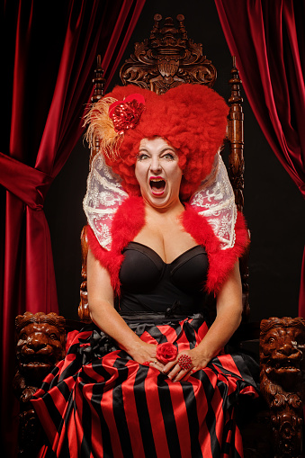 Queen of Hearts like female character on a throne in a studio shot