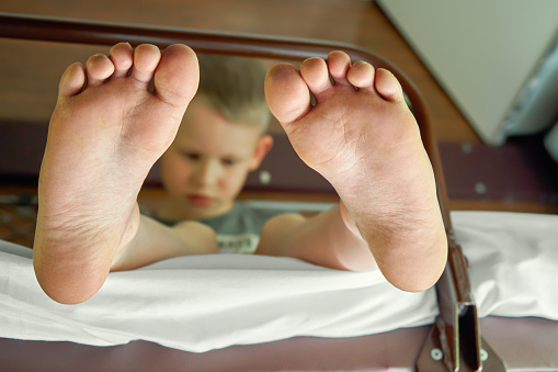 Feet close up. Soft focus barefoot boy sitting on mattress on upper sleeper while travelling by train