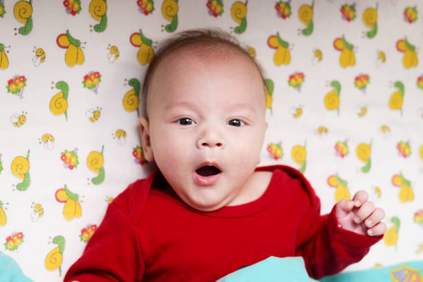 istock baby in red clothes is in bed and look at camera 1279314970