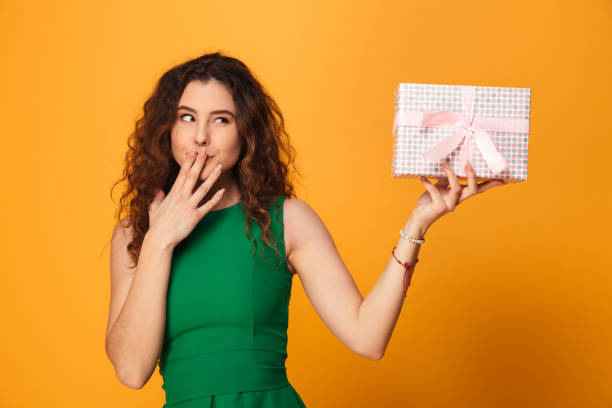 istock Pretty young woman holding present gift box. Looking aside. 1279315576