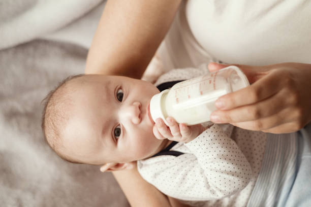 istock baby eats milk from a bottle and looks at camera 1279316695