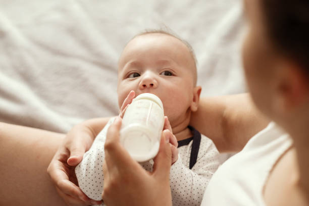 istock baby eats milk from a bottle and looks at camera 1279316704