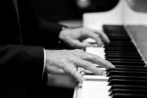 Close up side view of a Caucasian male playing a grand piano