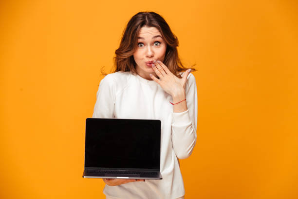 istock Confused brunette woman in sweater showing blank laptop computer screen 1279320524