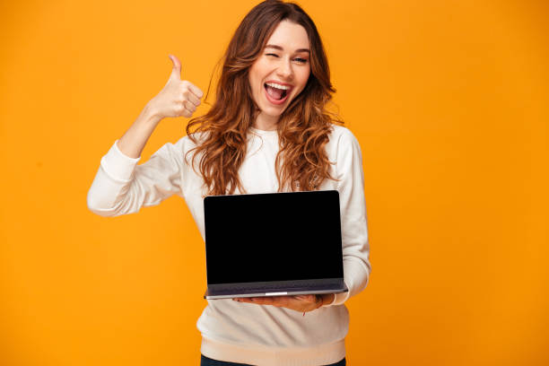 istock Cheerful brunette woman in sweater showing blank laptop computer screen 1279321578