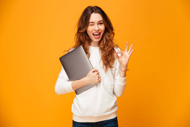 istock Cheerful young woman holding laptop computer showing ok gesture. 1279322021