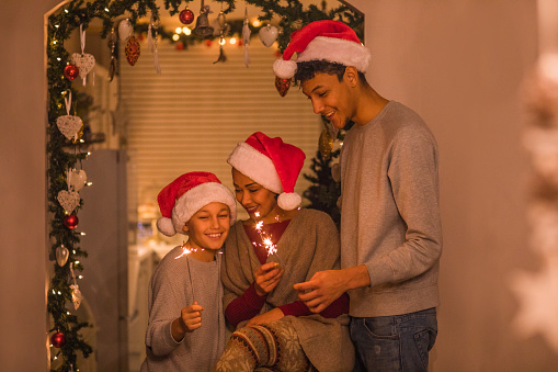Beautiful Black mixed race mother and two sons celebrating a family Christmas at their warm decorated home
