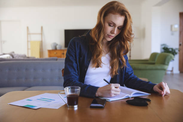 istock Woman taking notes while sitting on her desk at home 1279326740
