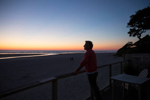 istock Mature man leans across railing near beach edge 1279331101