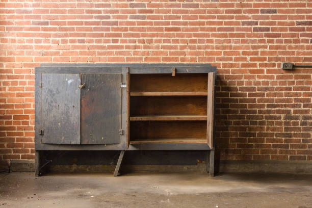 пустой шкаф оставили забытым на заброшенном заводе с красной кирпичной стеной - furniture office old warehouse стоковые фото и изображения