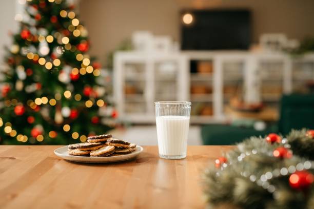 Milk and cookies for Santa Claus Still life photo of a plate with cookies and a glass of milk that is waiting for Santa Claus. In the back you can see a nice and cosy living room with decorated Christmas tree. No people. Copy space. Daylight. christmas cookies stock pictures, royalty-free photos & images